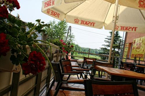 patio ze stołami, krzesłami i parasolem w obiekcie "Aleksandrówka" Restauracja i Noclegi w mieście Horyniec