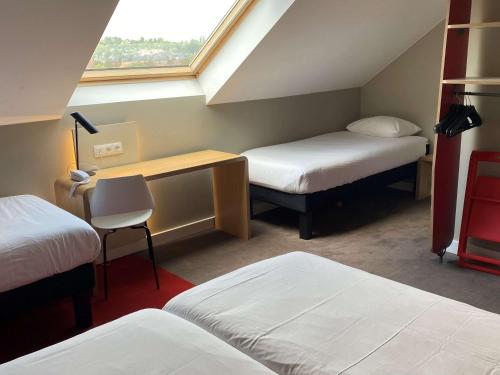 Cette chambre comprend deux lits, un bureau et une fenêtre. dans l'établissement Ibis Wavre Brussels East, à Wavre