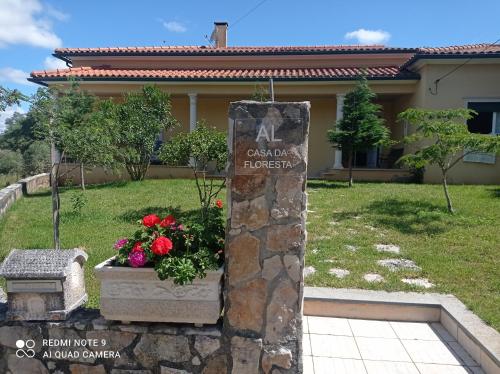 a sign in front of a house with flowers at Casa da Floresta in Santiago da Guarda