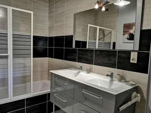 Un baño con lavabo, espejo y bañera. en Élégante maison de maître XVIIIe, jardin clos 500m², nature, proche Puy-en-Velay, 11 pers., cosy & confort - FR-1-582-315, en Arsac-en-Velay