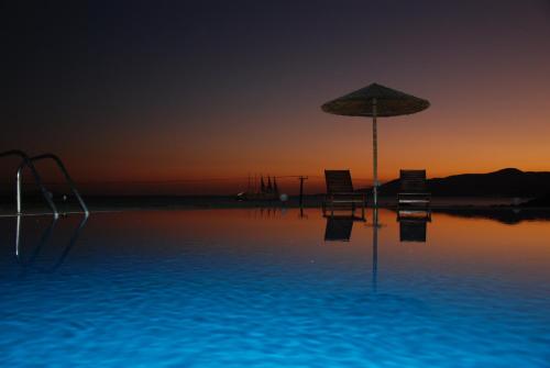 a swimming pool with an umbrella and chairs and a slide at Koulas Pension - Red Lake in Agios Prokopios