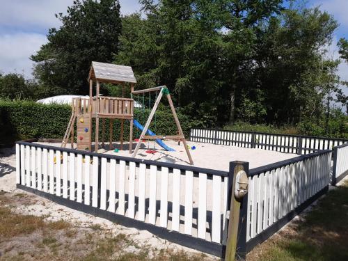 a playground in a yard with a white fence at Rejkjær Camping Hytter & Lejligheder in Ulfborg