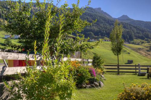 a garden in the mountains with a fence and flowers at Ausserwieserhof in Neustift im Stubaital