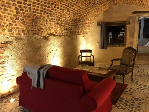 uma sala de estar com um sofá vermelho e uma mesa em Gîte semi-troglodytique du Vieux Chai de Trôo em Trôo