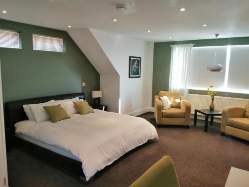 a bedroom with a large bed and two chairs at Lazy Days B&B in Broadstairs
