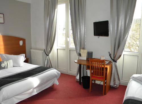 a bedroom with a bed and a desk and a tv at Alerion Centre Gare in Metz