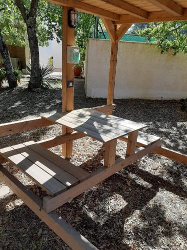 a wooden picnic table under a wooden shelter at Villaggio Camping Bosco Selva in Alberobello