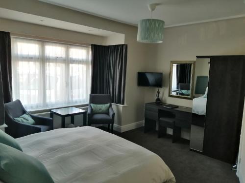 a hotel room with a bed and a desk and a mirror at Lazy Days B&B in Broadstairs