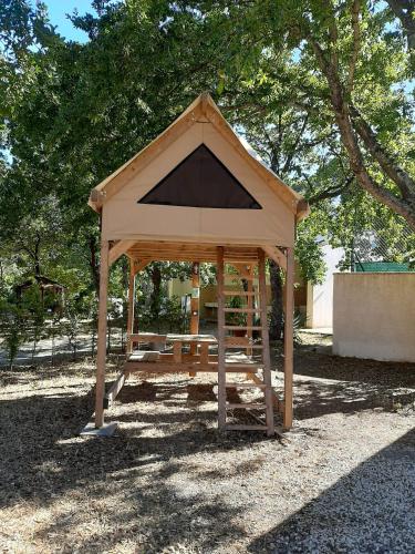 a wooden gazebo sitting in the shade of a tree at Villaggio Camping Bosco Selva in Alberobello