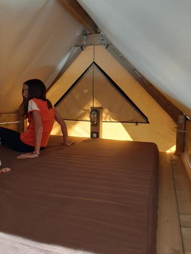 a woman sitting on a bed in a tent at Villaggio Camping Bosco Selva in Alberobello