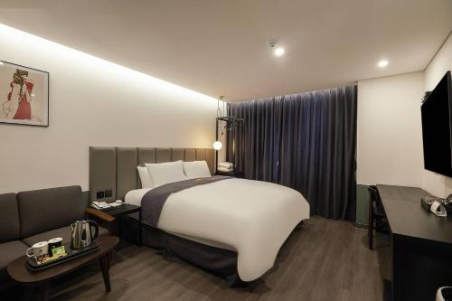 Habitación de hotel con cama grande y sofá en Namyangju Aone Hotel en Namyangju