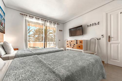 a bedroom with two beds and a tv on the wall at Tenerife South Apartments in Playa de las Americas