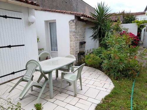 une table blanche et des chaises sur une terrasse dans l'établissement Maison à l'hortensia, à Sainte-Marie de Ré
