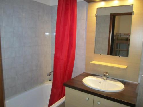 ein Badezimmer mit einem Waschbecken und einem roten Duschvorhang in der Unterkunft Studio Brides-les-Bains, 1 pièce, 4 personnes - FR-1-512-49 in Brides-les-Bains
