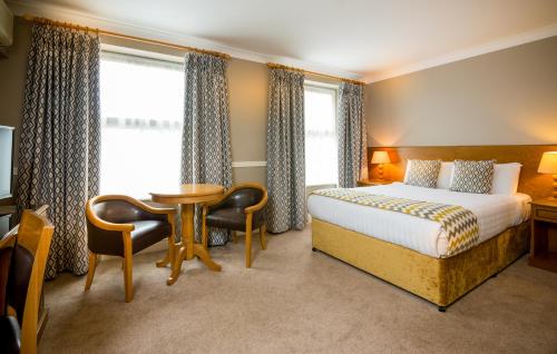 um quarto de hotel com uma cama, uma mesa e cadeiras em Tralee Benners Hotel em Tralee