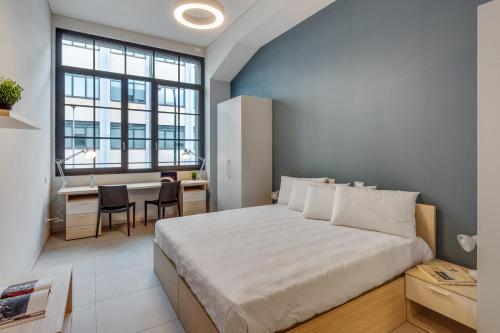 a bedroom with a large bed and a desk and a window at Camplus Regio Parco in Turin