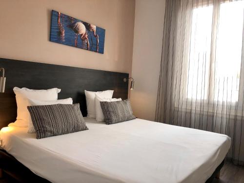 - une chambre avec un grand lit blanc et 2 oreillers dans l'établissement Hôtel Saint Louis, à Aigues-Mortes