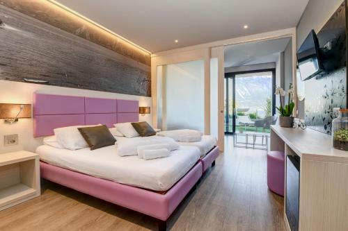 a bedroom with a large bed with a pink headboard at Hotel La Fiorita in Limone sul Garda