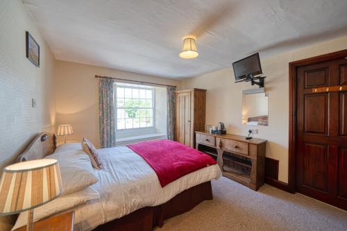 a bedroom with a bed and a desk and a television at The George and Dragon in Dent