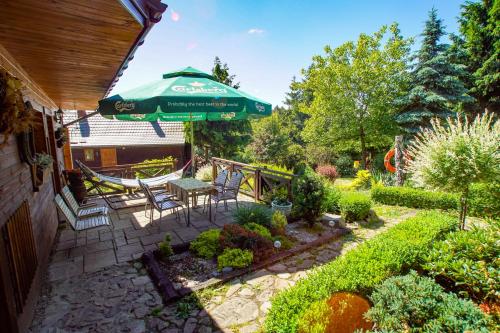 a patio with a table and a green umbrella at Chata Na Krańcu Świata in Łączna