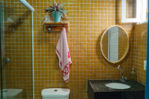 a yellow tiled bathroom with a toilet and a mirror at Casa duplex beira mar reformada com piscina no Peito Moça in Luis Correia
