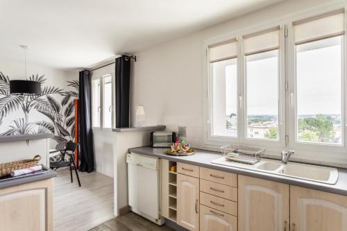 une cuisine avec un évier et deux fenêtres dans l'établissement Blanche de Castille- Rond point de Paris, à Nantes