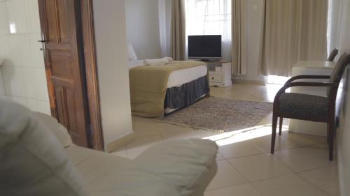 uma sala de estar com uma cama e uma televisão em Kaz Breeze Gardens em Kampala