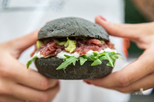 a person holding a sandwich in their hands at Marangon Apartments in Sùtrio