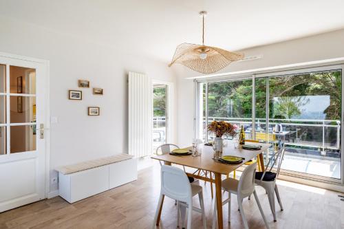 une salle à manger blanche avec une table et des chaises en bois dans l'établissement Villa Sterne - maison vue mer exceptionnelle - Fréhel, à Fréhel