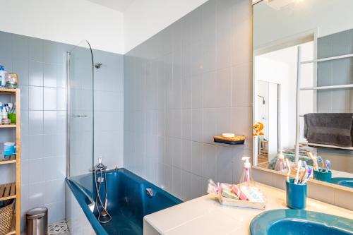 Un baño con bañera azul y espejo. en Villa Sterne - maison vue mer exceptionnelle - Fréhel, en Fréhel