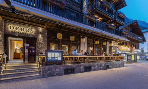 a bar with people sitting outside of a building at Hotel Derby in Zermatt
