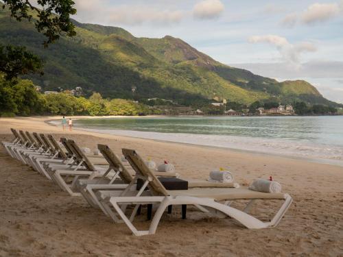 una fila di sedie a sdraio sulla spiaggia di Savoy Seychelles Resort & Spa a Beau Vallon