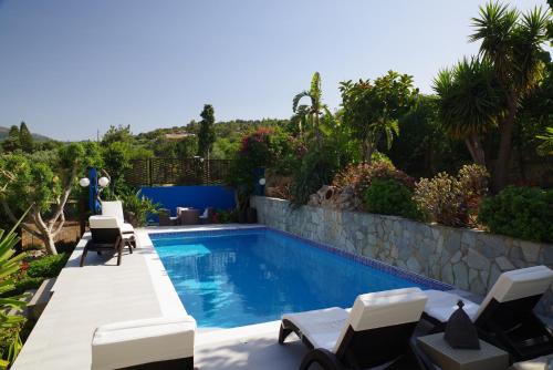 una piscina con tumbonas y sillas alrededor en Villa Pegasus, en Agios Nikolaos