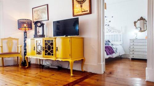 a living room with a television on a yellow cabinet at Find Me Inn Boutique Penthouse in Lisbon