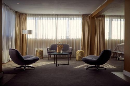 a hotel room with two chairs and a table and a bed at Van der Valk Hotel Emmeloord in Emmeloord