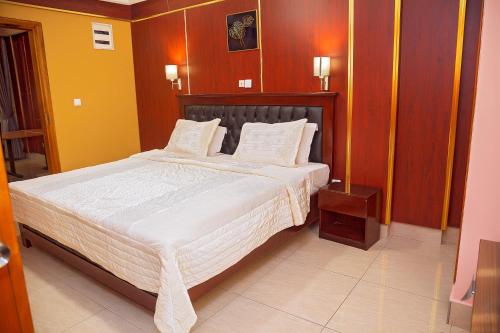a bedroom with a large bed with white sheets at NOUBOU INTERNATIONAL HOTEL BONAPRISO in Douala