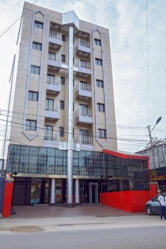 a tall building with a red fence in front of it at NOUBOU INTERNATIONAL HOTEL BONAPRISO in Douala