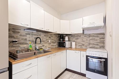 a white kitchen with white cabinets and a sink at Cozy House Ania in Plitvička Jezera