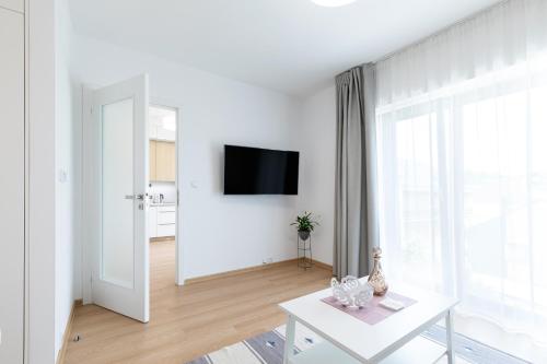 a white living room with a white table and a tv at RASL House in Luka nad Jihlavou