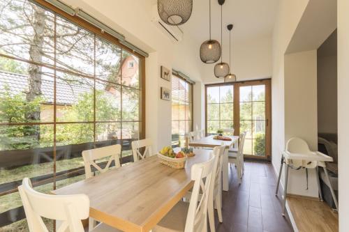 a dining room with a table and chairs and large windows at Cozy House Ania in Plitvička Jezera