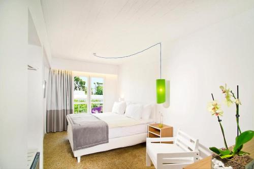 a white bedroom with a white bed and a window at Marathon Beach Resort in Nea Makri