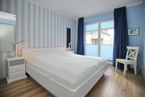 1 dormitorio con 1 cama, 1 silla y 1 ventana en Dünenblick Wohnung 42, en Boltenhagen