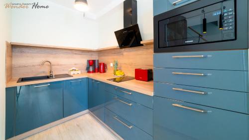 a kitchen with blue cabinets and a microwave at Wonder Home - Apartamenty położone blisko deptaka, licznych restauracji i sklepów in Karpacz