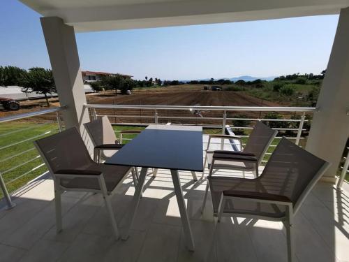 a table and chairs on a balcony with a view of a field at Ionion Beach Apartment Hotel & Spa in Arkoudi