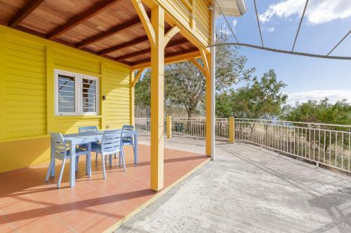 a yellow house with a table and chairs on a deck at Le Palma Christi in Le Carbet