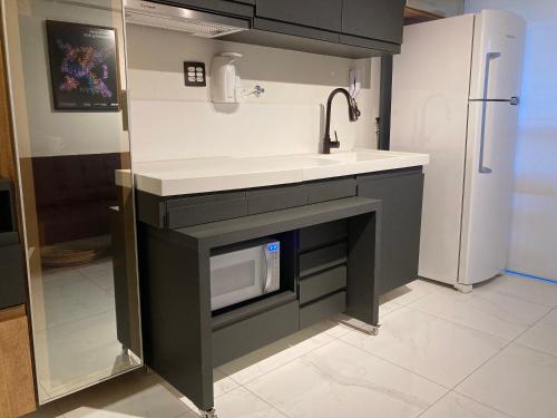 a kitchen with a sink and a microwave at Studio Lux West Flat in Mossoró
