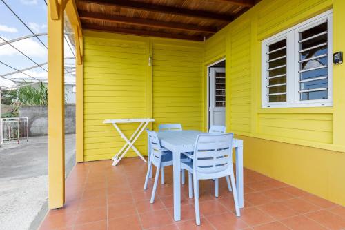 a table and chairs on the porch of a yellow house at Le Palma Christi in Le Carbet