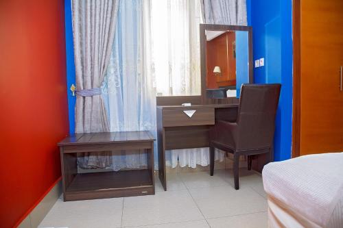 a bedroom with a desk with a mirror and a bed at NOUBOU INTERNATIONAL HOTEL BONAPRISO in Douala