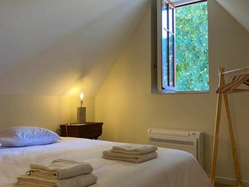 a bedroom with a bed with towels on it at Gîte élégant avec jardin privé, climatisation et parking à Ainay-le-Vieil - FR-1-586-7 in Ainay-le-Vieil
