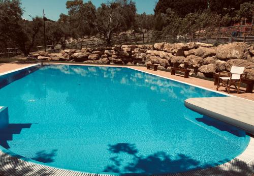 a blue swimming pool with a bench and some rocks at Agriturismo DonnoMarco in Simeri